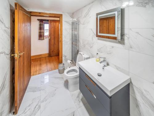 a white bathroom with a toilet and a sink at Mill Moor - B6064 in Pooley Bridge