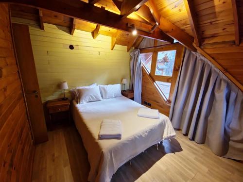 a bedroom with a bed in a wooden cabin at El Remanso - Arrayan Cabin, Bahía Manzano in Villa La Angostura