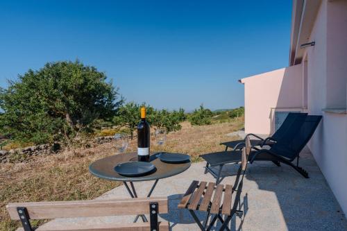 a table with a bottle of wine and chairs on a patio at Il Sughereto In Vigna in Aglientu