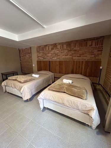 two beds in a room with a brick wall at Hotel Villa D'Angelo in Itatiba