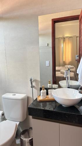 a bathroom with a sink and a toilet and a mirror at Chalet Paraíso Lençóis Santo Amaro in Santo Amaro