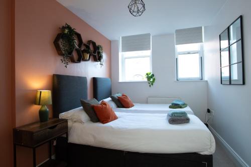 a bedroom with a bed with white sheets and orange pillows at 1-Bed Apartment in Bournemouth centre in Bournemouth