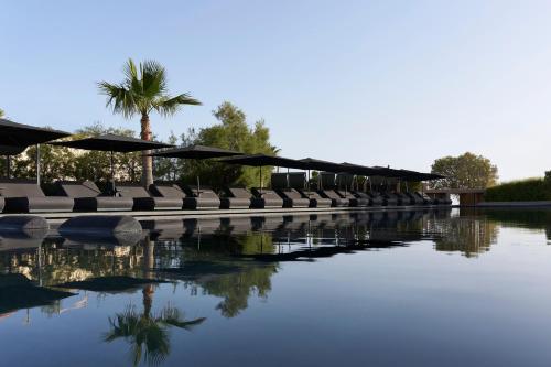 a row of chairs and umbrellas next to a body of water at NEMA Design Hotel & Spa - Adults Only in Hersonissos