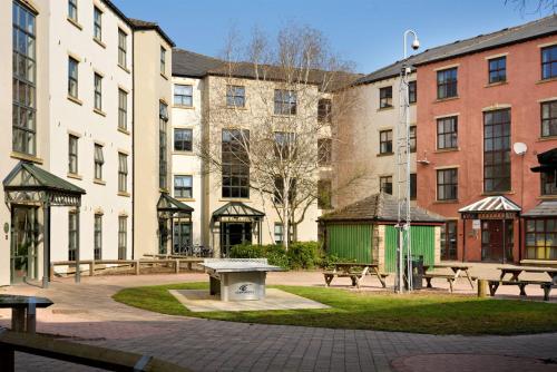 a park with benches in front of buildings at For Students Only - Snow Island in Huddersfield in Huddersfield