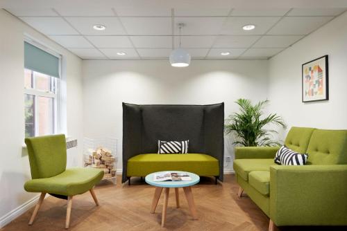 a waiting room with two green chairs and a table at For Students Only - Snow Island in Huddersfield in Huddersfield