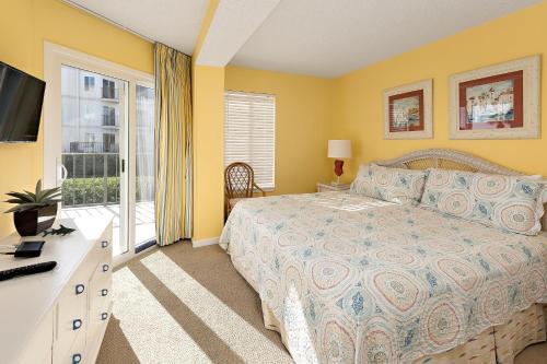 ein Schlafzimmer mit einem Bett, einem Fernseher und einem Fenster in der Unterkunft Beach Club #111 in Saint Simons Island