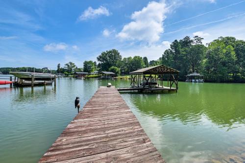 a dock on a lake with a person standing on it at Launch and Dock Lake Norman Retreat with Scenic Deck in Mooresville