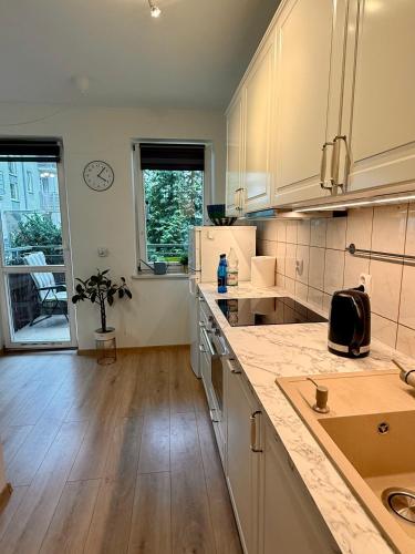 a kitchen with white cabinets and a wooden floor at Kraków Nest in Kraków