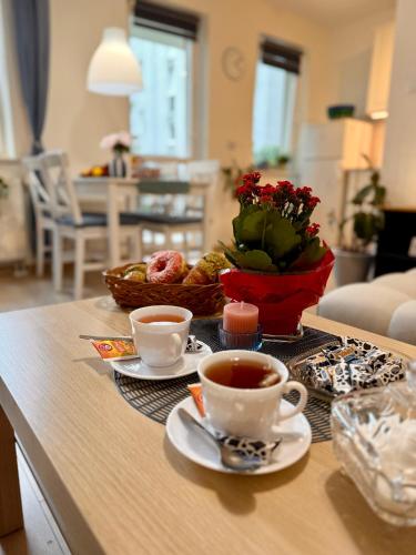 a table with two cups of coffee and a basket of flowers at Kraków Nest in Kraków