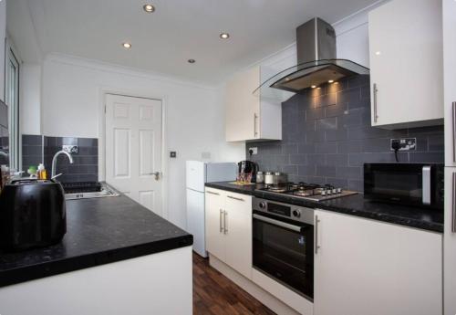 a kitchen with white cabinets and black counter tops at 3BR Retreat High Barnes Wifi in Sunderland