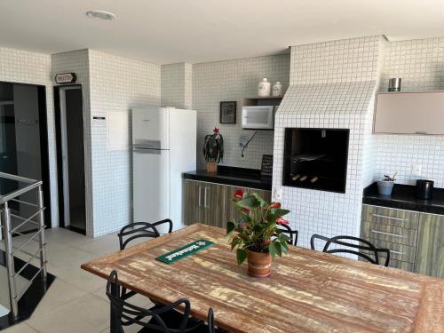 eine Küche mit Holztisch und Kühlschrank in der Unterkunft 2 Suítes, até 4 pessoas, Piscina e Churrasqueira - Praia do Forte! in Cabo Frio