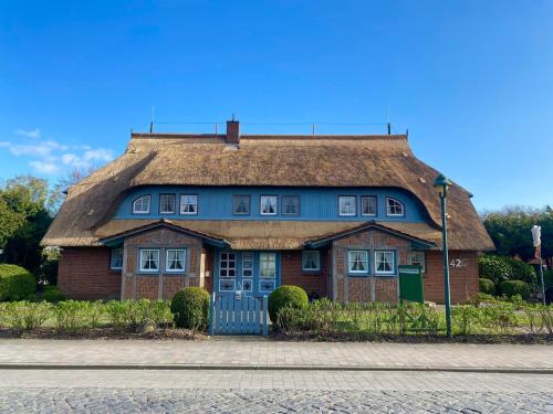 ein großes Backsteinhaus mit einem Strohdach in der Unterkunft Ferienwohnung Nr 01 EG in Born