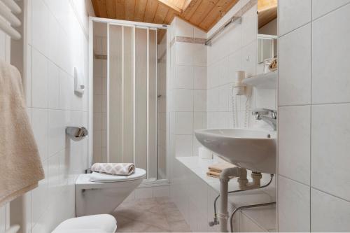 a white bathroom with a toilet and a sink at Unterdornerhof Algund in Lagundo