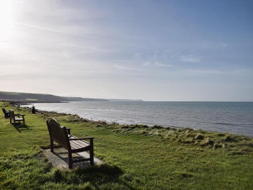 two benches sitting on the grass near the water at Glasfor in Llanon
