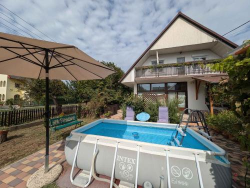 a pool with an umbrella next to a house at Apartment Balatonboglar 7 in Balatonboglár