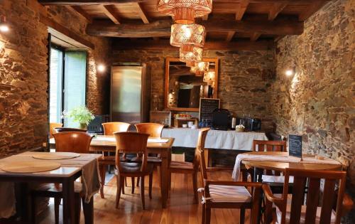 restauracja ze stołami i krzesłami oraz kamienną ścianą w obiekcie Fogar de Lecer w mieście Arzúa