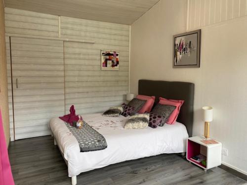 a bedroom with a large white bed with pink pillows at Chez Cathy in LʼHoumeau