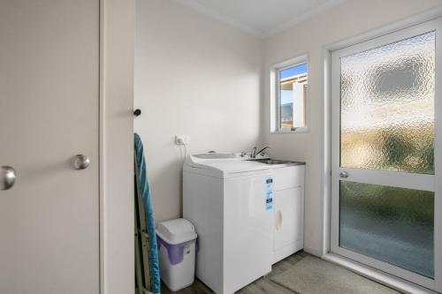 a small bathroom with a sink and a window at Golden Dawn in Waihi Beach