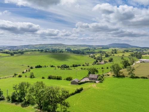 an aerial view of a green pasture with an old barn at Paradise in Gisburn