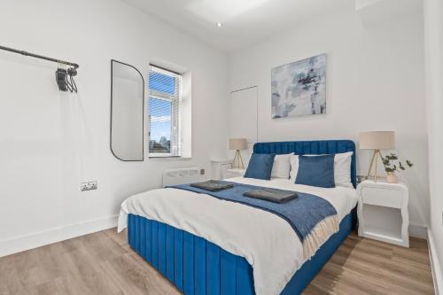 a bedroom with a blue bed and white walls at Cardiff Luxe Flats with Spa Facilities in Cardiff