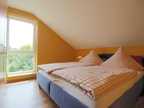 a bed in a room with a large window at FeWo Golfblick in Wittenbeck