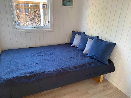 un letto con lenzuola blu in una stanza con finestra di Cozy Summer House By The Østersøbadet a Rødby