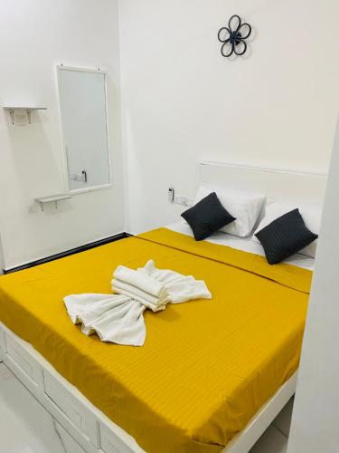 a bedroom with two beds with yellow sheets and a mirror at Hotel Jay R in Trincomalee