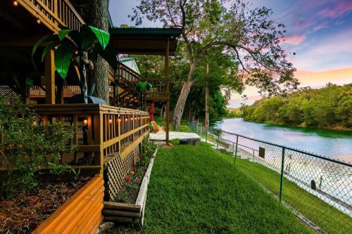 a house with a fence next to a river at Charming Green Riverfront Stay, New Braunfels in New Braunfels