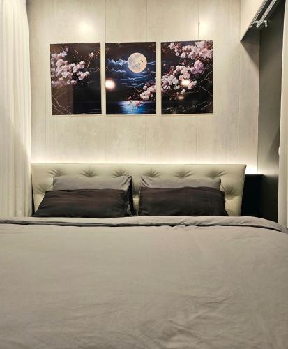 a bedroom with a bed with four pictures on the wall at Free Airport Pick Up ! 12th Floor Cozy Studio Room, 5 mins walk to IconSiam & BTS in Bangkok