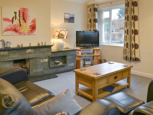 a living room with a fireplace and a tv at Quiet Ways in Portinscale
