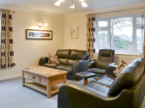 a living room with leather furniture and a table at Quiet Ways in Portinscale