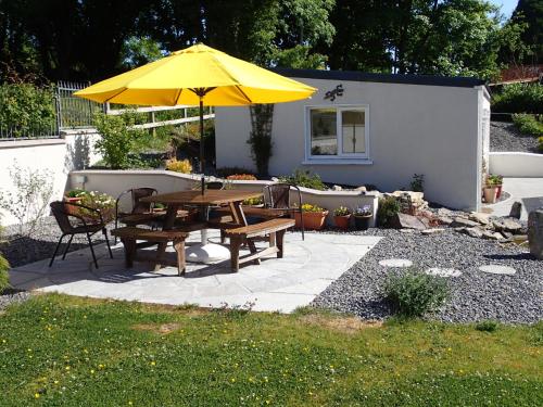 a patio with a table and a yellow umbrella at Lough Gara Lodge Self Catering in Gorteen