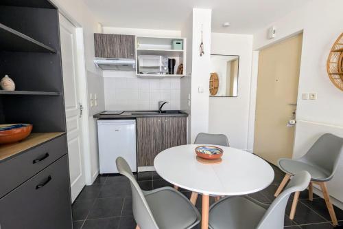 une petite cuisine avec une table et des chaises blanches dans l'établissement T2 with terrace near Les Minimes, à La Rochelle