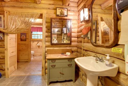 a bathroom in a log cabin with a sink and mirror at Handcrafted Log Cabin in Candor Group Getaway! in Candor