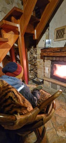 a room with a stone fireplace and a rocking chair at Babiogórskie Domki in Lipnica Wielka