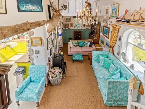 a living room with a couch and chairs in a caravan at Willow Cottage in St Just