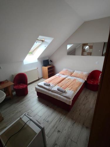 a bedroom with a bed and two red chairs at Willa Solna in Kołobrzeg