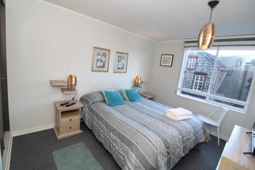 a bedroom with a bed with blue pillows and a window at Comodo Departamento Cercano al Centro y el Lago in Puerto Varas