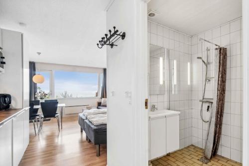 a white bathroom with a shower and a bedroom at Lovely Holiday Apartment Consumption Included in Allinge