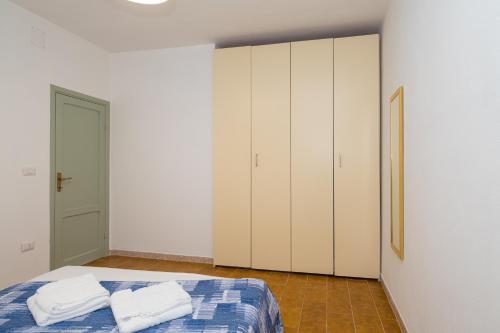 a bedroom with white cabinets and a bed with two towels at Casa Vacanze - Platamò in Platamona