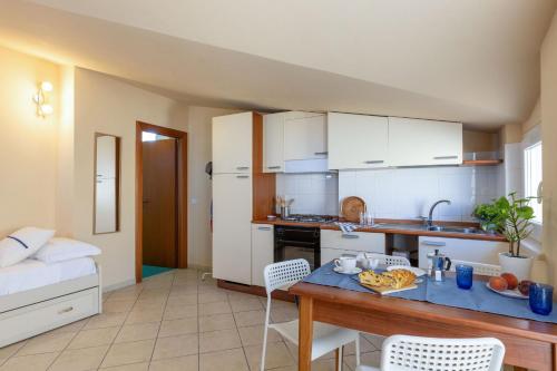 a kitchen with white cabinets and a table and chairs at Italian Experience-Sweet Conero in Porto Recanati
