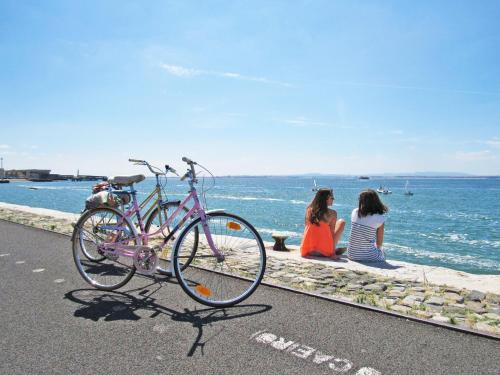 
a woman standing next to a bike on the beach at Lookout Lisbon Hostel in Lisbon
