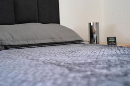 a bed with a gray comforter and a pillow at Ferienwohnung Zum Steiger in Bleicherode