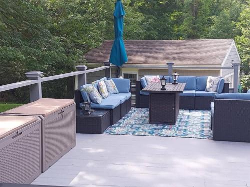 a patio with couches and a table and an umbrella at 597b) Large 4 bedroom - Pool - Fire Pit in Wolcott