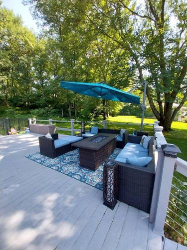 a patio with couches and a blue umbrella at 597b) Large 4 bedroom - Pool - Fire Pit in Wolcott