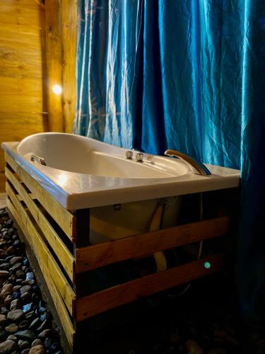a bath tub in a bathroom with a blue shower curtain at Moivaro Eco Hostel in Nkunjila