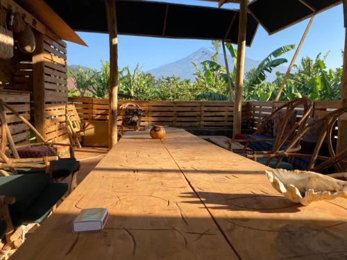 a long wooden table on a porch with a mountain in the background at Moivaro Eco Hostel in Nkunjila