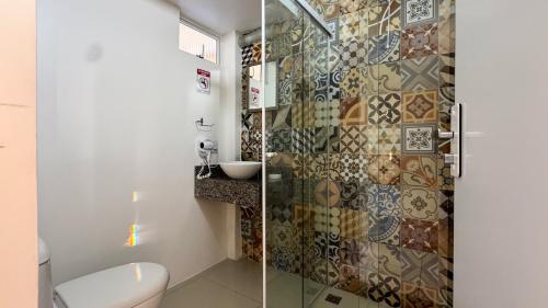 a bathroom with a toilet and a glass shower at Pousada Vila do Navegante in Bombinhas