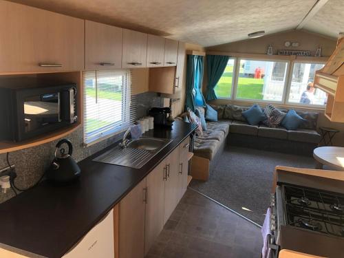 an rv kitchen and living room with a couch at The Retreat Palm - Lido Beach in Prestatyn