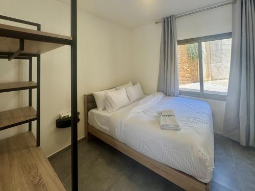 AfqāにあるAstra Faqra 3BR w Pool and Balconyの白いシーツと窓のあるベッドのある寝室